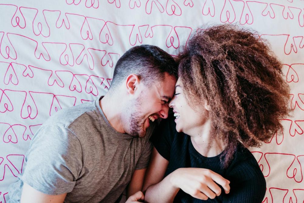 Slow Sex Paar im Bett lachend