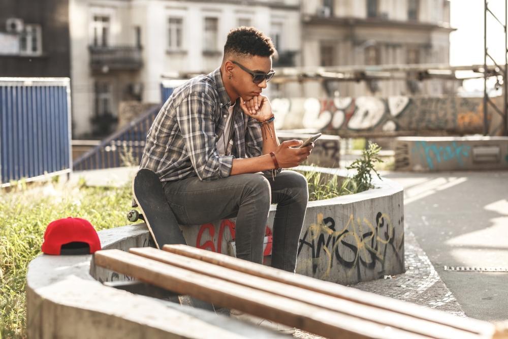 Welche_Dating_App_passt_zu_welchem_Ziel_Mann_sitzt_im_park_und_schaut_auf_seine_Dating_App