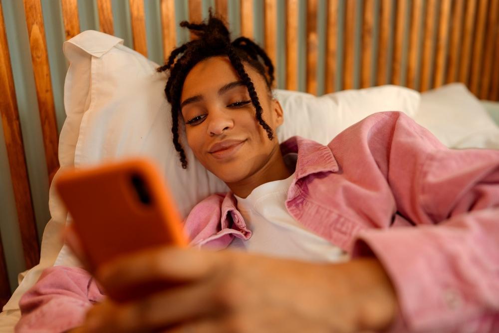 FAQ_zu_Wie_sicher_ist_Poppen.de_Frau_liegt_auf_ihrem_bett_und_schaut_in_bearbeitet_ihr_profil_auf_poppen_de_