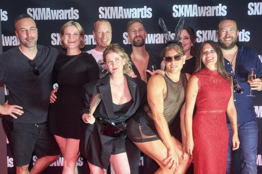 POPCORN_und_FET_am_gemeinsamen_Stand_auf_dem_SX_Festival_2026_Gruppenfoto_vor_rotem_Hintergrund__.jpg
