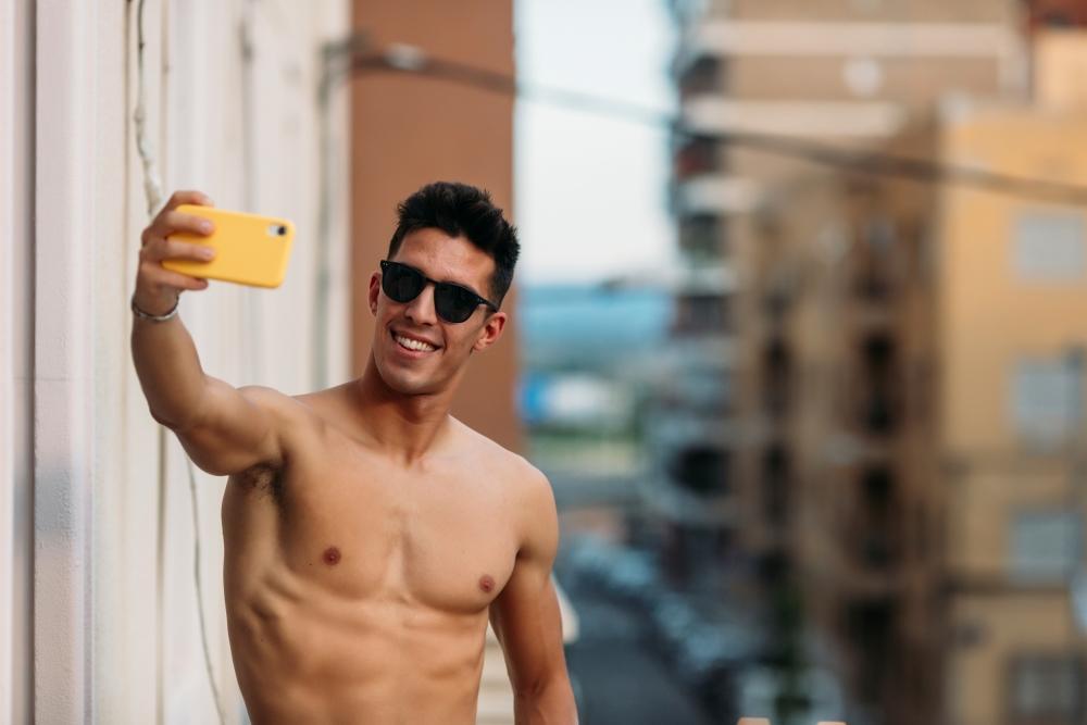 Penisbilder_und_dickpics_Mann_steht_auf_dem_Balkon_und_macht_mit_seinem_handy_ein_selfie_fuer_ein_Penisbild_.jpg