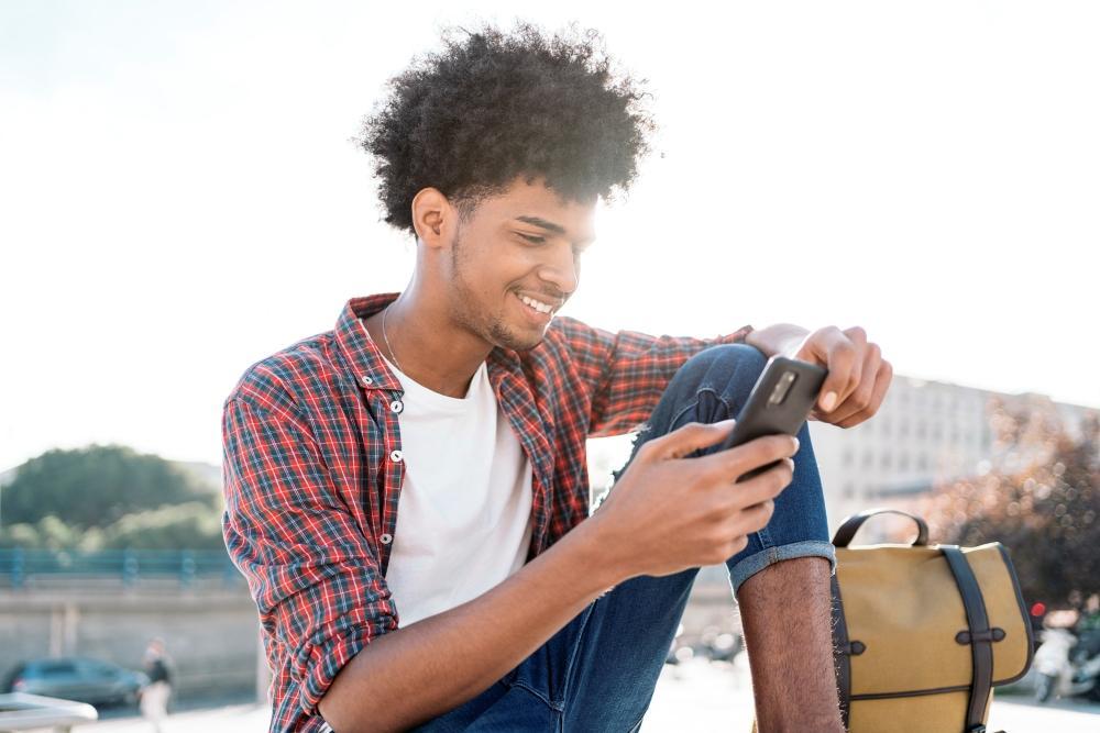Casual_Date_kosten_Lieber_mobil_flirten_Mann_sitzt_draußen_und_schaut_auf_seine_Casual_Dating_App_und_xhattet_mit_seinem_Date_